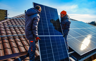 Deux personnes en train d'installer des panneaux solaires sur un toit.